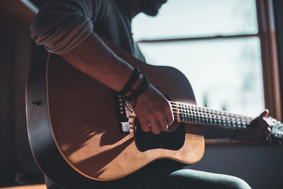 Man playing acoustic guitar selective focus photography