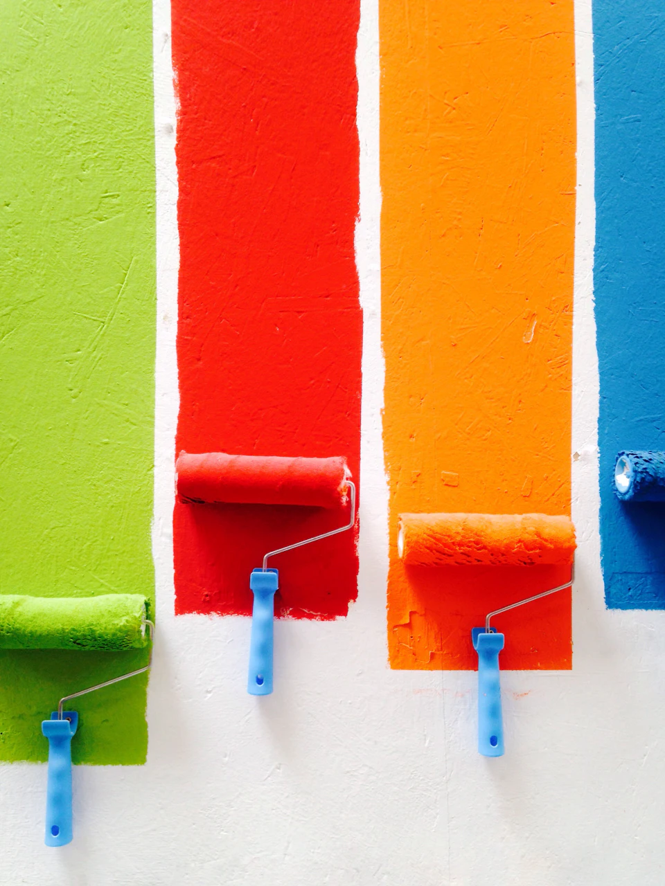 Four orange, green, blue, and red paint rollers