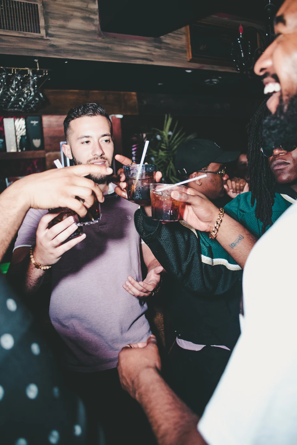 A group of people toasting with glasses of dark drinks in a bar