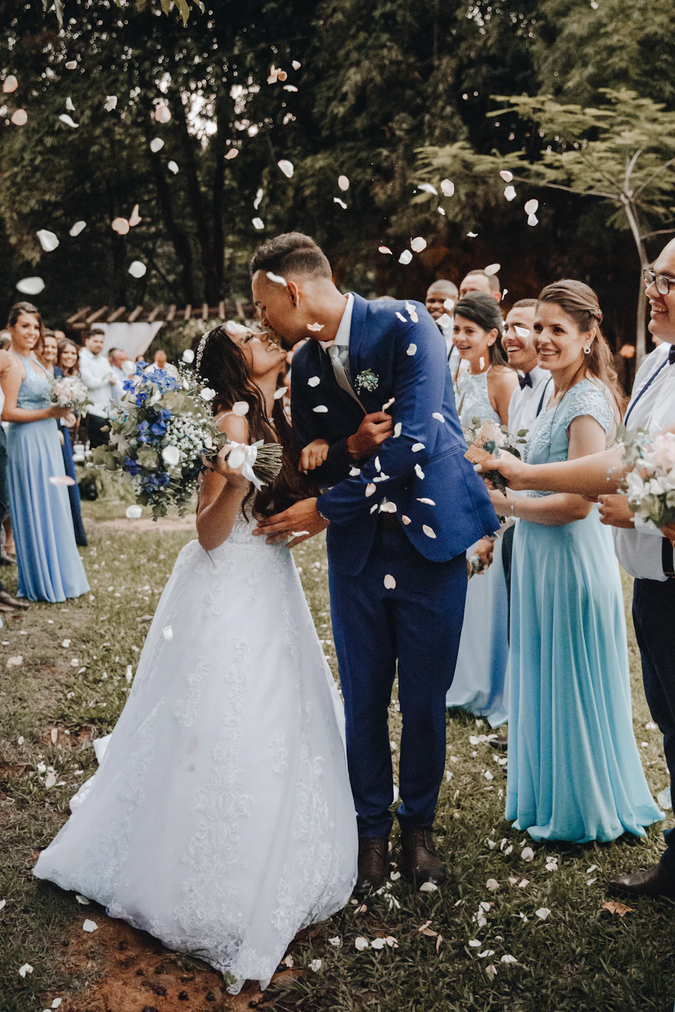 Man in blue suit kissing woman in white wedding dress