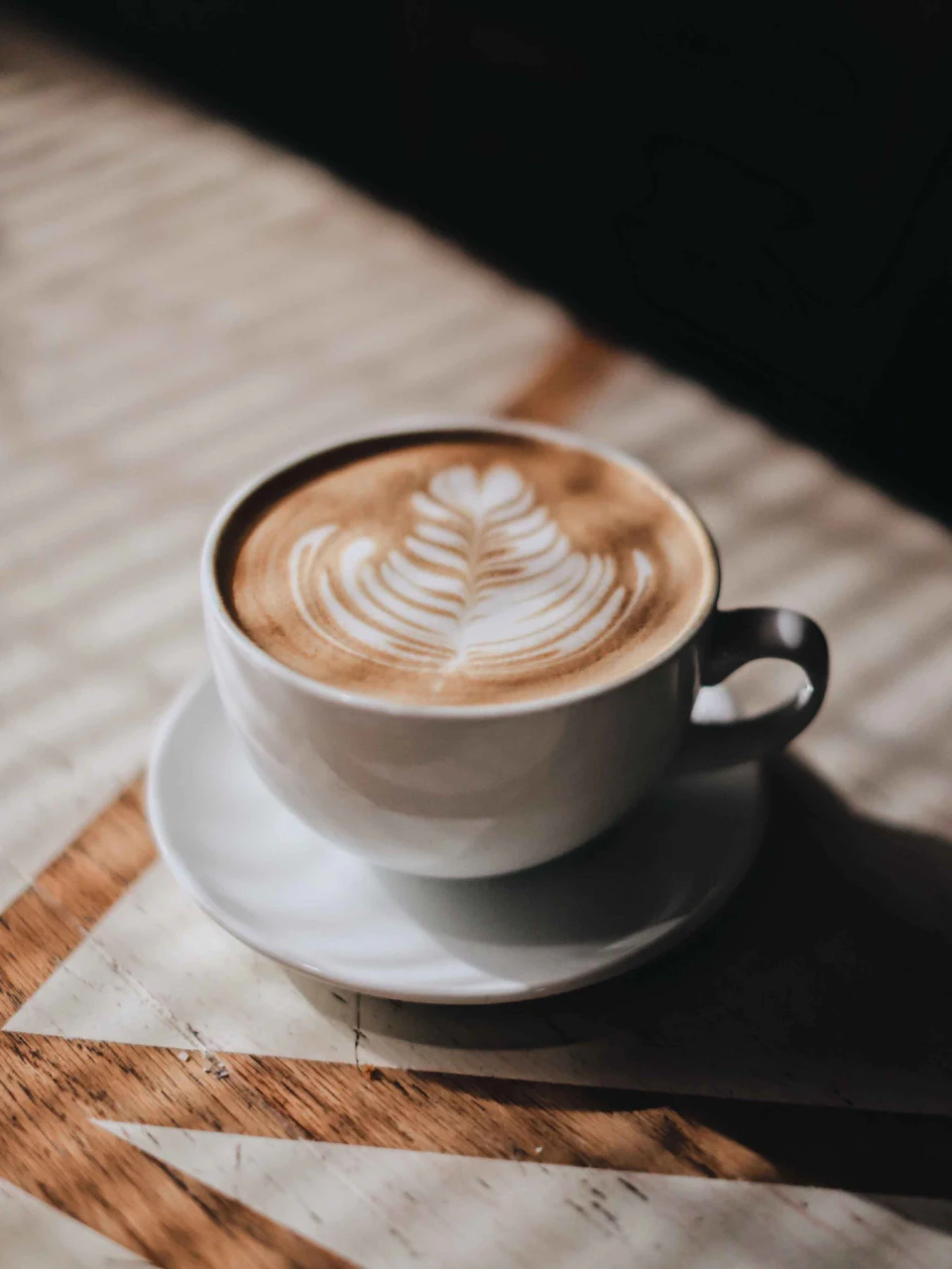 White ceramic cup with saucer on brown wooden table