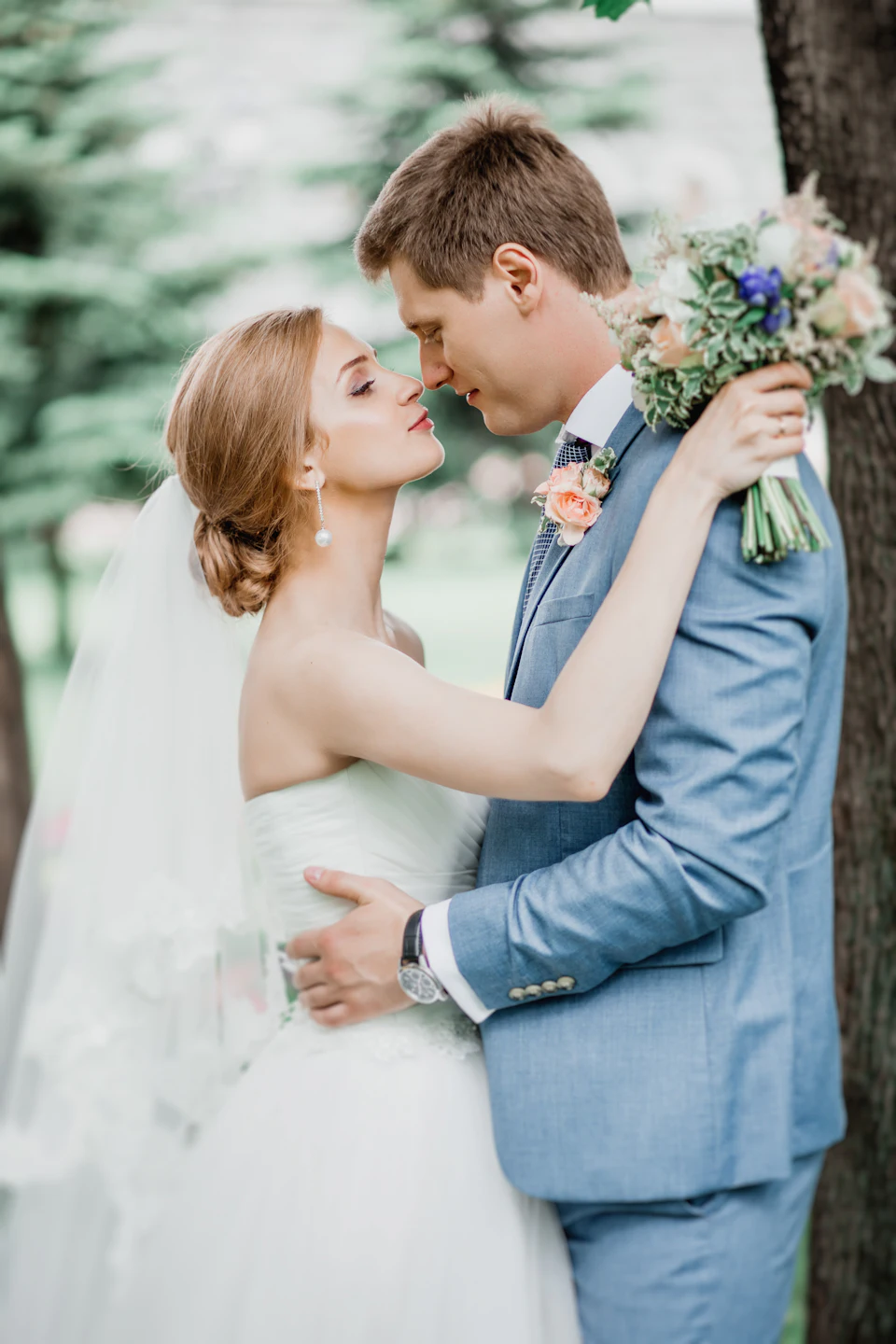 Man in gray suit kissing woman in white dress