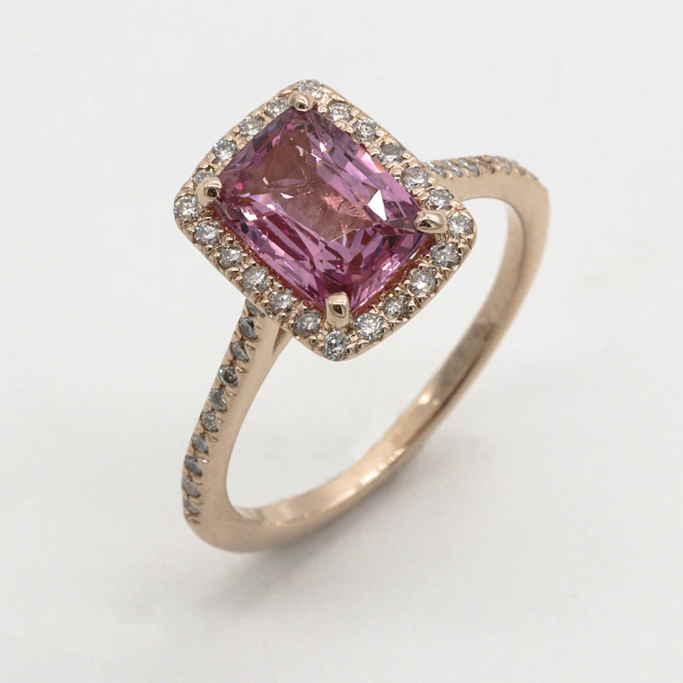 A rose gold ring with a rectangular pink gemstone surrounded by small diamonds