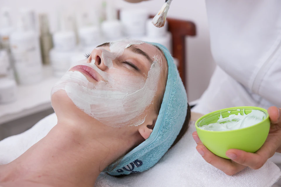 Woman lying on blue towel with white cream on face