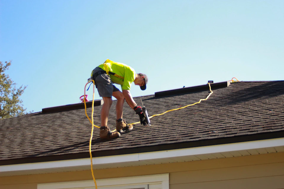 A man working on a roof with a power drill